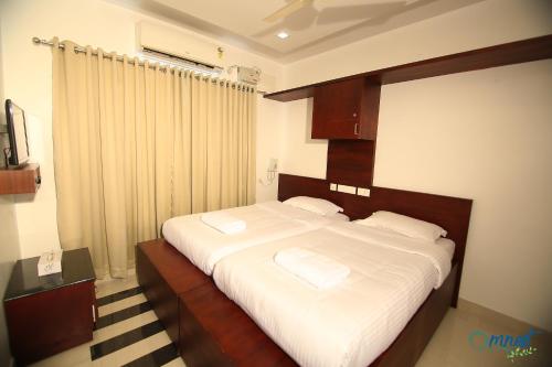 a bedroom with a large bed with white sheets and pillows at Omnest in Cochin
