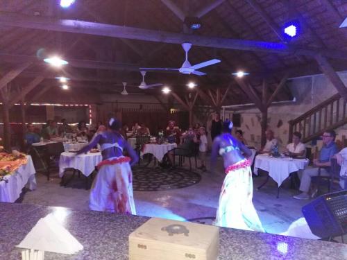 two women are dancing in a room with tables at Eden Villa in Belle Mare