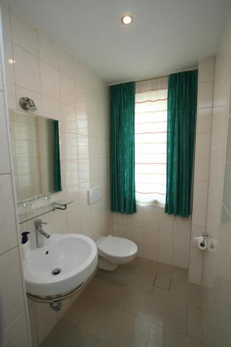 a bathroom with a sink and a toilet and a window at Pension Gestüt Lindenhof in Templin