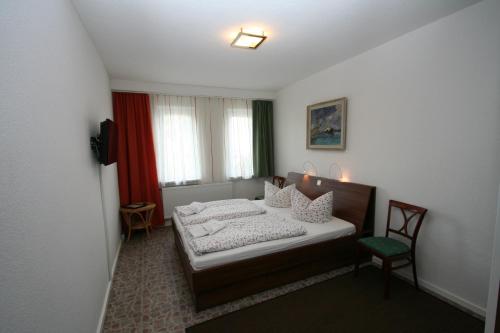 ein kleines Schlafzimmer mit einem Bett und einem Stuhl in der Unterkunft Pension Gestüt Lindenhof in Templin