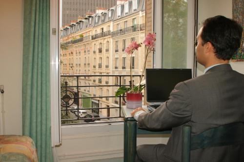 mężczyzna siedzący przed oknem z laptopem w obiekcie Printania Porte de Versailles w Paryżu
