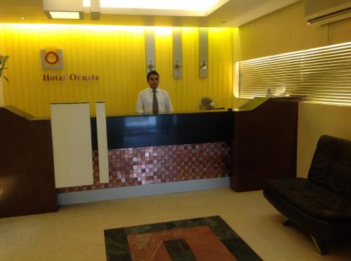 a man standing at the counter of a hotel office at Hotel Ornate in Dhaka