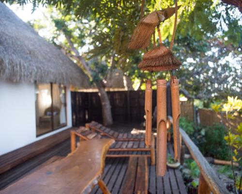 a patio with a bench and a straw umbrella at Vila la Mar Vilanculo in Vilanculos