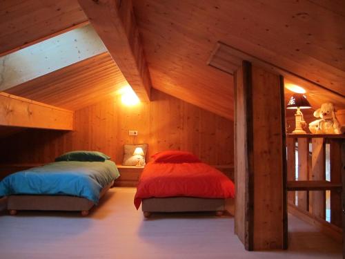 two beds in a room with wooden walls at La maison de Marie in Valmorel