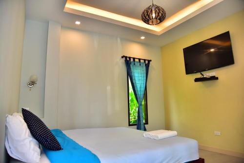 a bedroom with a bed and a tv on the wall at The House at Pranburi in Pran Buri