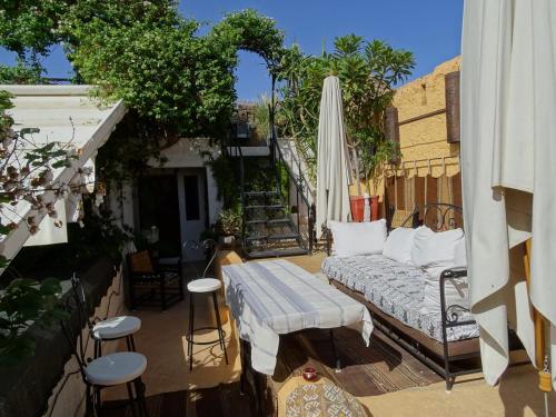 an outdoor patio with a couch and an umbrella at Dar Oulhoum in Marrakesh