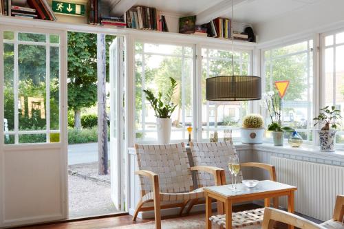 sala de estar con ventanas, mesa y sillas en Karnelund Krog & Rum, en Simrishamn