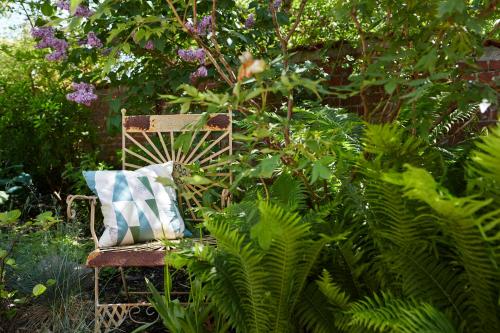 a chair with a pillow sitting in a garden at Karnelund Krog & Rum in Simrishamn