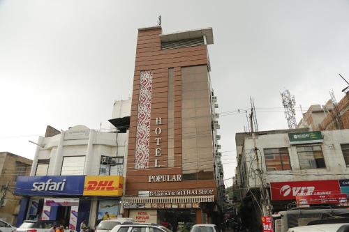 a tall building on a city street with cars at Hotel Popular in Amritsar