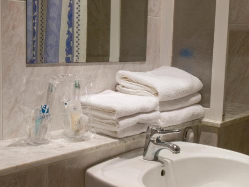 baño con lavabo y una pila de toallas en Hotel Marcial en Narón