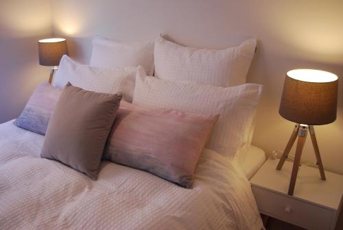 un letto bianco con cuscini e 2 lampade; di Balcony Retreat Apartment by Ready Set Host a Melbourne