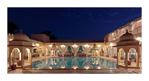 a large building with a swimming pool at night at Rohet Garh in Rohat
