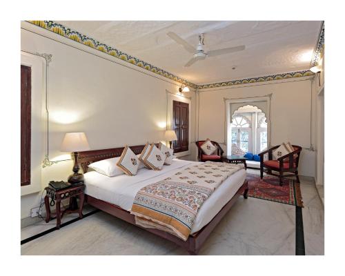 a bedroom with a large bed and two chairs at Rohet Garh in Rohat