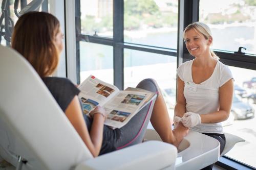 two women sitting in a waiting room reading a magazine at Hotel Borovnik in Tisno
