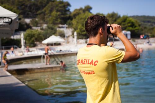 a man taking a picture of a body of water at Hotel Borovnik in Tisno