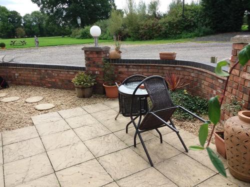 a patio with two chairs and a brick wall at The Stables - Deer Park Farm in Solihull