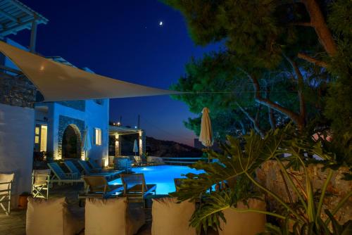 a patio with a swimming pool at night at Yperia Hotel in Aegiali