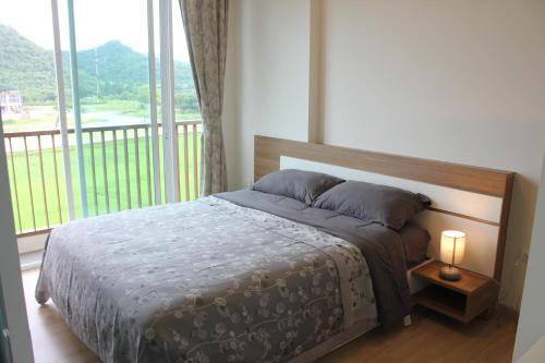 ein Schlafzimmer mit einem Bett und einem großen Fenster in der Unterkunft Baan Khao Yai in Pak Chong