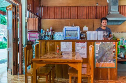 a man is standing behind a wooden table with a tableablish at Sarm Mork Guest House in Mae Hong Son