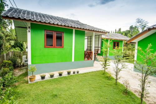 a green house with a red window and a yard at Sarm Mork Guest House in Mae Hong Son