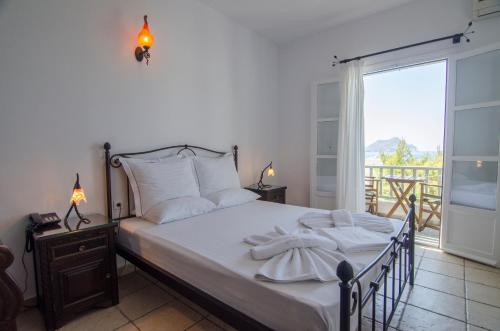 a bedroom with a bed with white sheets and a balcony at Yperia Hotel in Aegiali