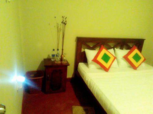 a bedroom with two beds and a night stand with at Osheen Family Guest House in Polonnaruwa