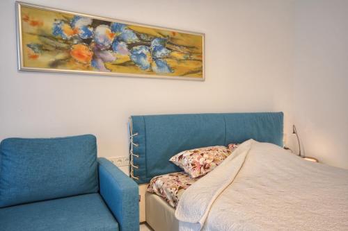 um quarto com uma cama e uma cadeira azul em Snow Apartment em Druskininkai