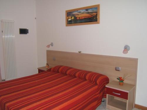 ブレンゾーネにあるAppartamenti Maryのベッドルーム1室(オレンジ色のストライプ毛布付きのベッド1台付)