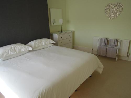 a bedroom with a large white bed and a dresser at Special seafront apartment in Portsmouth