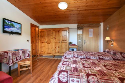a bedroom with two beds and a television in a cabin at Albergo Adele in Bormio