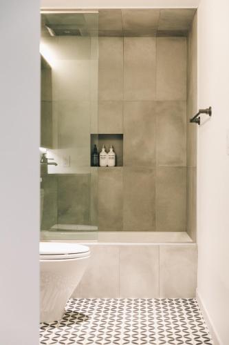 a bathroom with a shower with a toilet and a sink at The Surfrider Malibu in Malibu