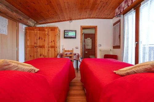two beds in a room with red sheets at Albergo Adele in Bormio