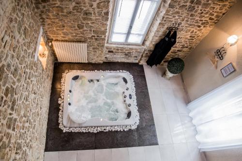 a large bath tub in a room with a brick wall at Au domaine des anges, 3 gîtes luxueux avec Jacuzzi privatif, sauna, mini-piscine, piscine extérieure chauffée en saison in Bain-de-Bretagne