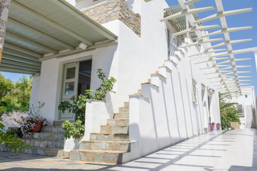 a white house with a white fence and stairs at Yperia Hotel in Aegiali