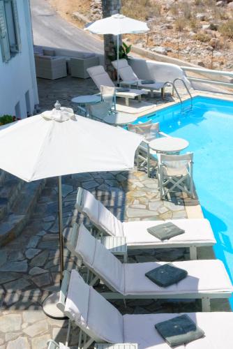 a pool with white umbrellas and chairs next to a pool at Yperia Hotel in Aegiali
