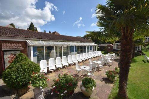 a patio area with chairs, tables and umbrellas at Laguna Hotel in Bournemouth