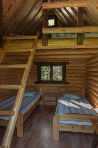 two beds in a log cabin with two windows at Pinnamäe Holiday House in Partsi