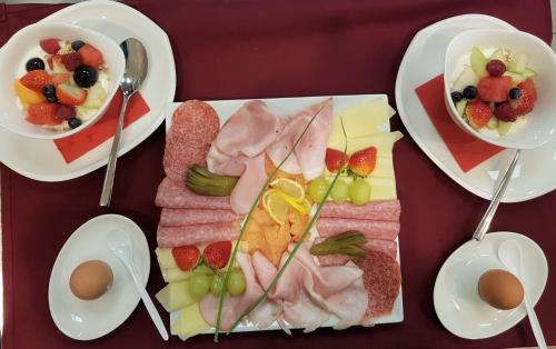 a table with plates of food and bowls of fruit at Aparthotel AlpTirol in Kaltenbach