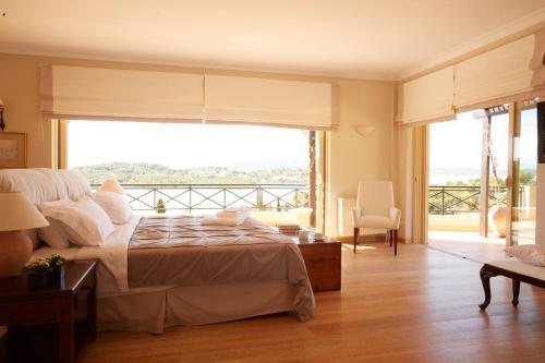a bedroom with a bed and a large window at Beachfront Villa in Porto Heli