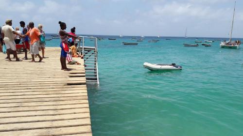 a group of people standing on a pier with a boat in the water at Sal Apartments Djadsal Moradias in Santa Maria