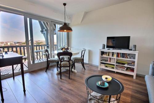 un salon avec une télévision et une table avec des chaises dans l'établissement Deauville Paradise, à Deauville