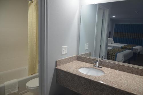 a bathroom with a sink and a toilet and a mirror at Travelers Inn in Rosenberg