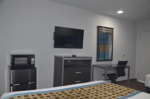 a bedroom with a bed and a desk and a flat screen tv at Travelers Inn in Rosenberg