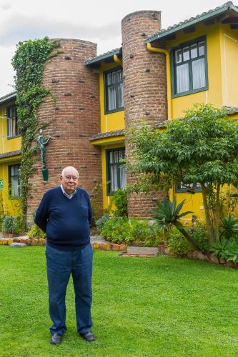 a man standing in front of a yellow house at Hostal Saint Mary´s Tababela in Tababela