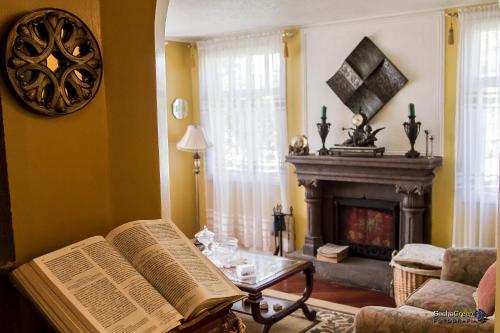 a living room with a fireplace and a book on a table at Hostal Saint Mary´s Tababela in Tababela