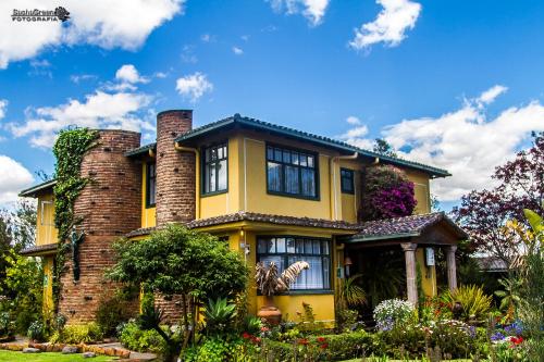 a yellow house with plants and flowers at Hostal Saint Mary´s Tababela in Tababela