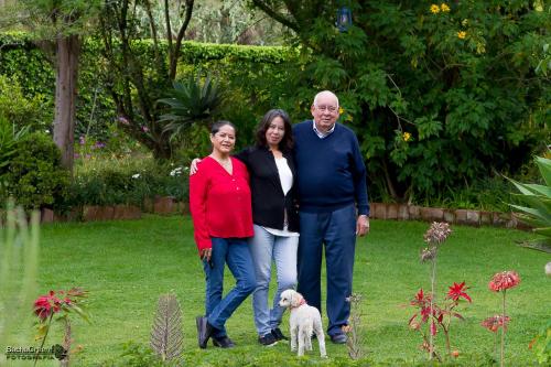 a family posing for a picture in a garden with a dog at Hostal Saint Mary´s Tababela in Tababela
