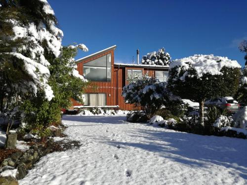 a house in the snow with snow covered trees at The bach in Saint Arnaud