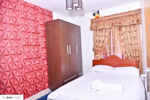 1 dormitorio con 1 cama con pared roja en Outlink Skyline Minutes to JKIA airport en Nairobi