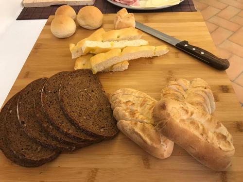 a wooden cutting board with bread and a knife at Casa Soave B&B in Alba